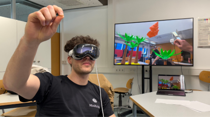 Student teste die VR-Brille. Im Hintergrund sieht man auf dem Bildschirm die Applikation.