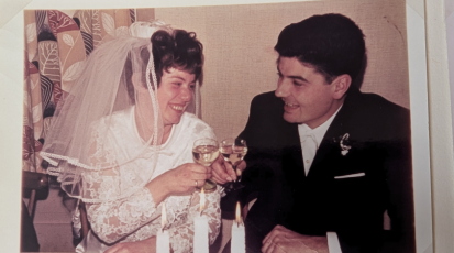 Oma und Opa stoßen an ihrer Hochzeit mit einem Glas Wein an.