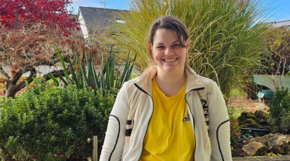 Tatjana Kühr lächelt in die Kamera. Hinter ihr ist der Garten zu sehen.