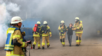 Feuerwehr im Einsatz und holen Frau aus brennenden Gebäude