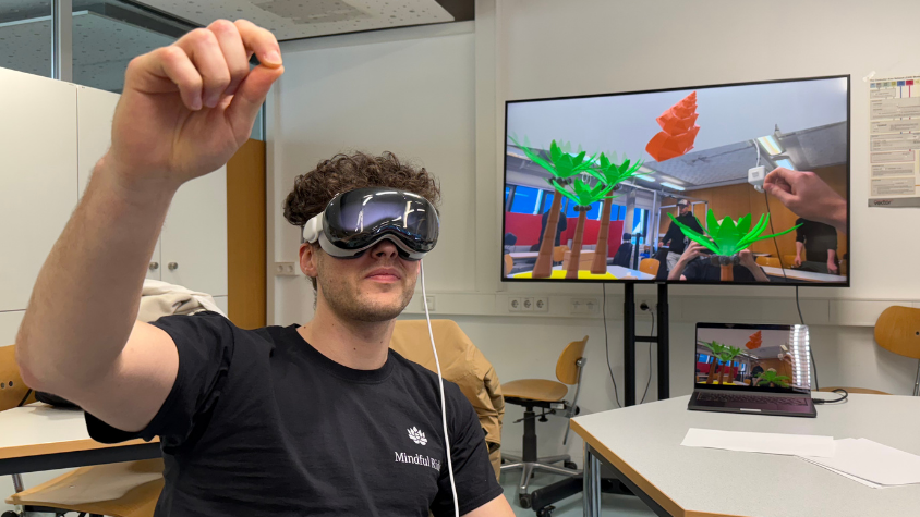 Student teste die VR-Brille. Im Hintergrund sieht man auf dem Bildschirm die Applikation.