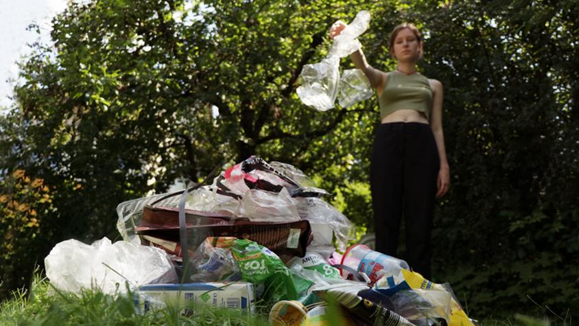 Frau wirft Plastik auf Plastikberg