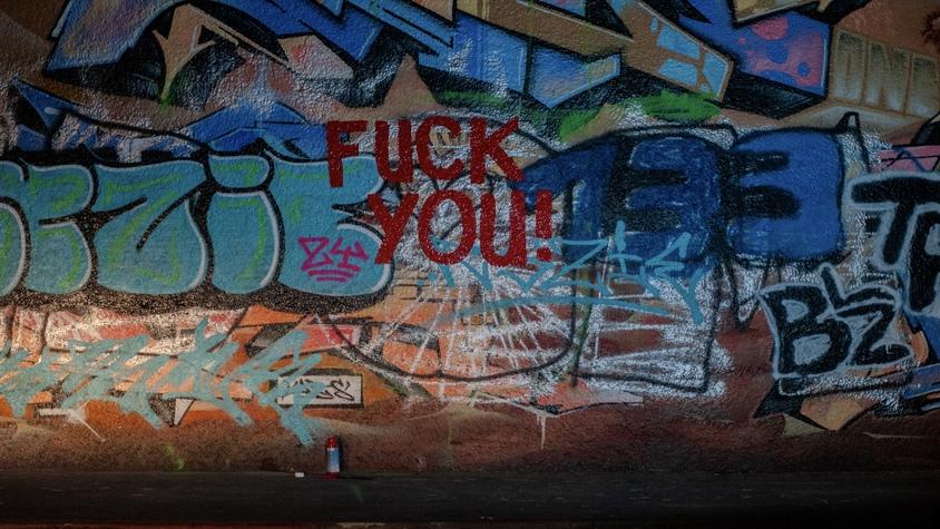 Graffiti-Wand mit rotem "Fuck you"-Schriftzug