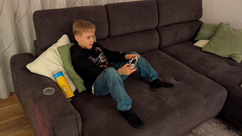 Ein Kind sitzt auf der Couch und spielt an der Konsole