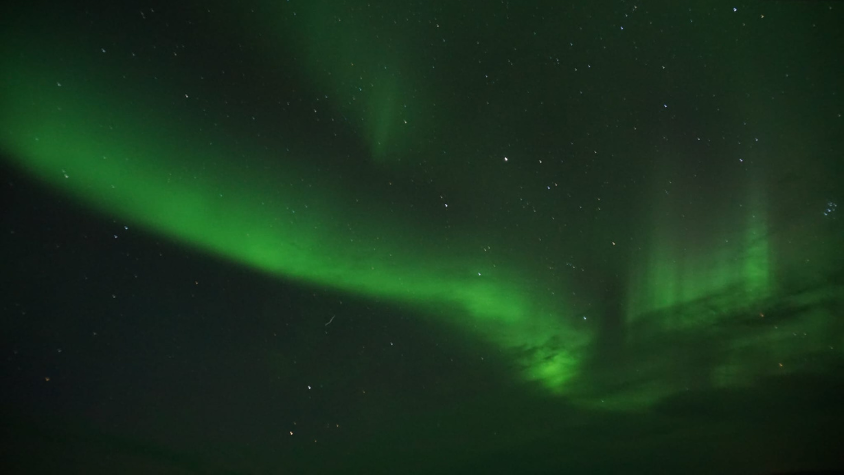 Auf dem Bild sieht man einen dunklen Himmel und ein grünes Polarlicht.