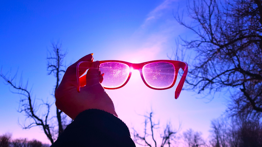 Pinke Brille vor rosa-blauem Himmel