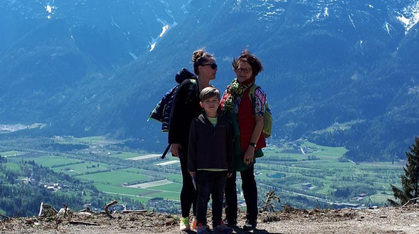 Eine Frau und eine ältere Dame stehen zusammen mit einem Jungen vor einer Berglandschaft in Österreich. | Quelle: Irmgard Tinz