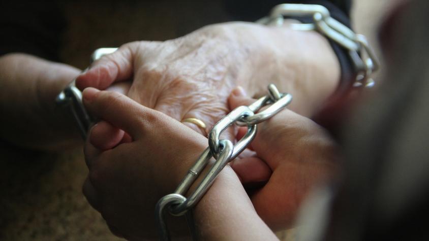 Die zusammengelegten Hände einer jungen und einer älteren Frau sind in Ketten gelegt