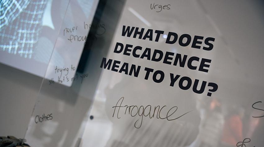 Eine Glaswand mit der Aufschrift "What does decadence mean to you?".