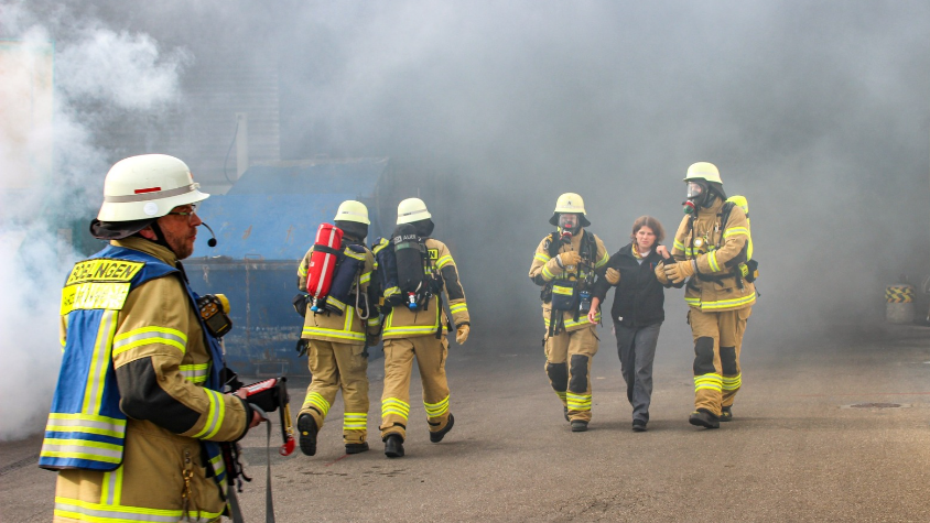 Feuerwehr im Einsatz und holen Frau aus brennenden Gebäude