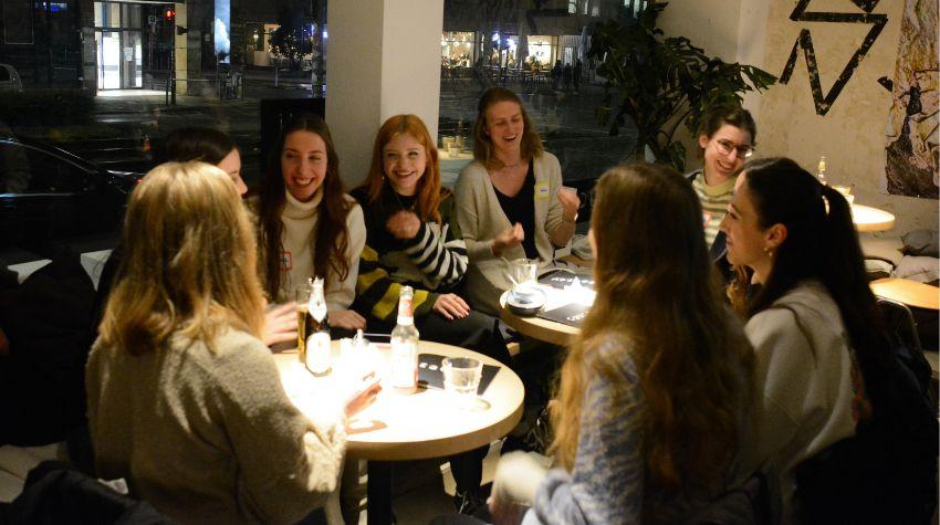zu sehen ist eine Gruppe von junger Frauen in einer Bar die sich unterhalten und lachen