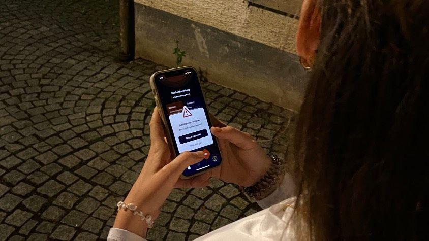 Alleine draußen bei Nacht, geöffnete App „Liv“, um die Achtsamkeit zu erhöhen.