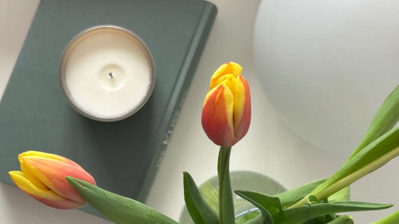 Tulpen und ein Buch auf dem eine Kerze steht