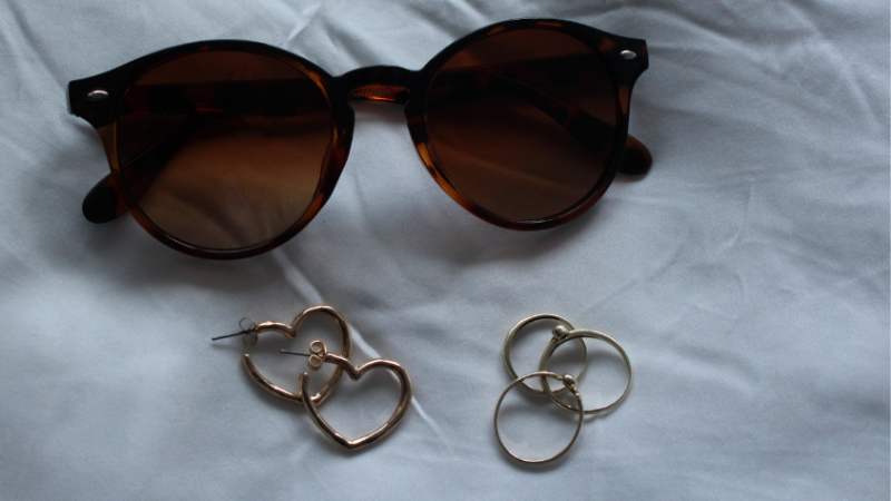 Sonnenbrille und Ohrringe vor weißem Hintergrund